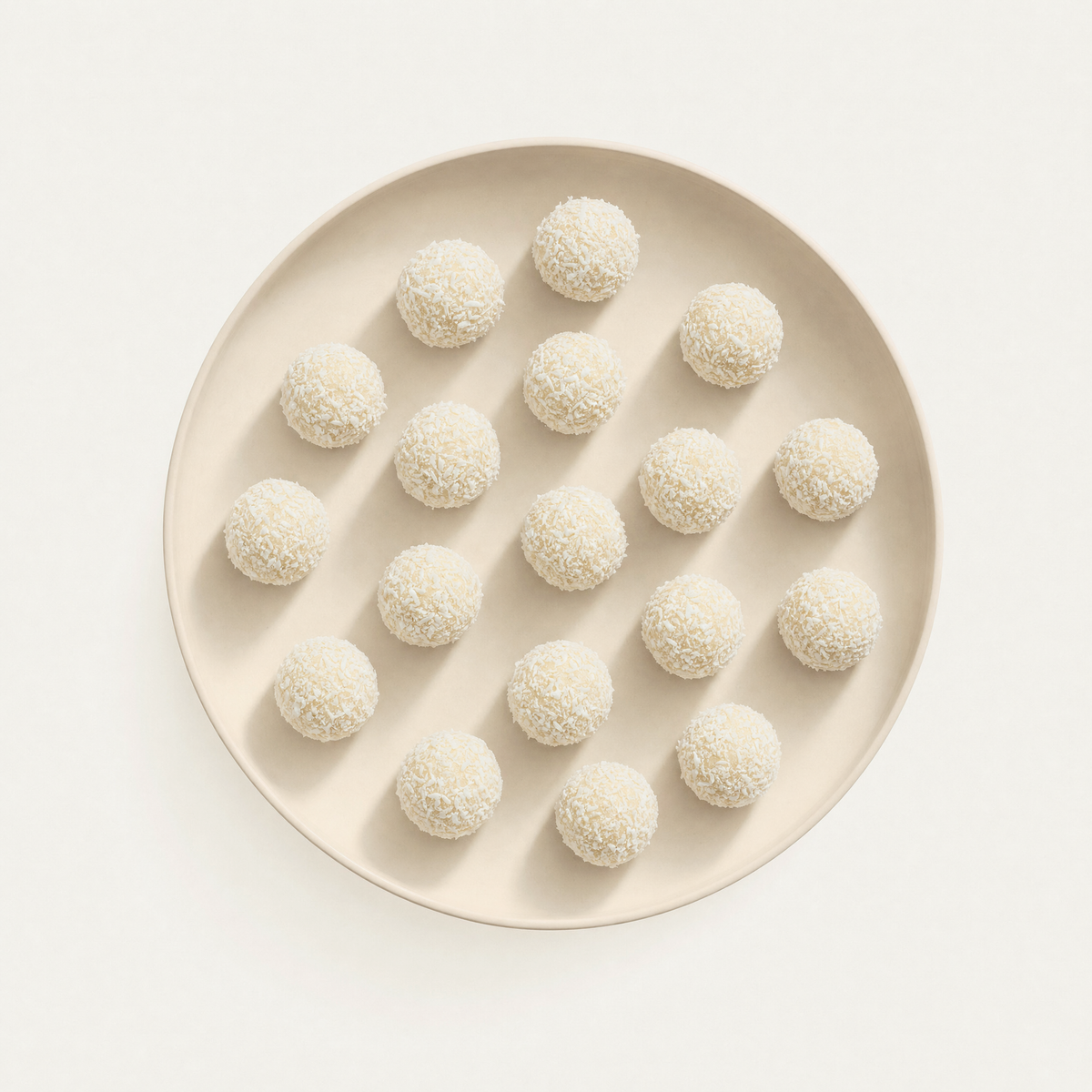 Coconut bliss balls on a cream plate, overhead